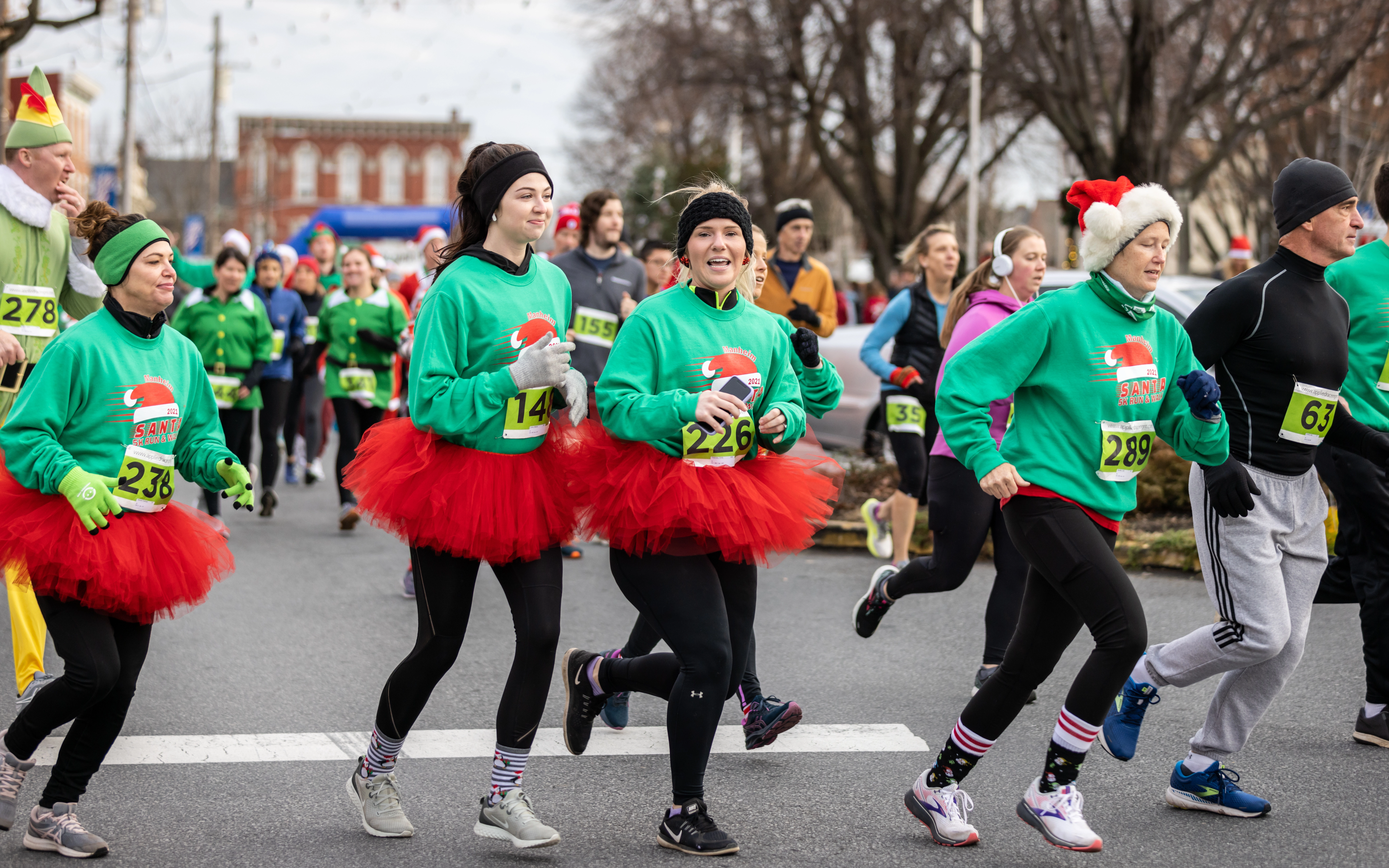 A group of runners wearing holiday tutus during the Santa 5K Run & Walk.
